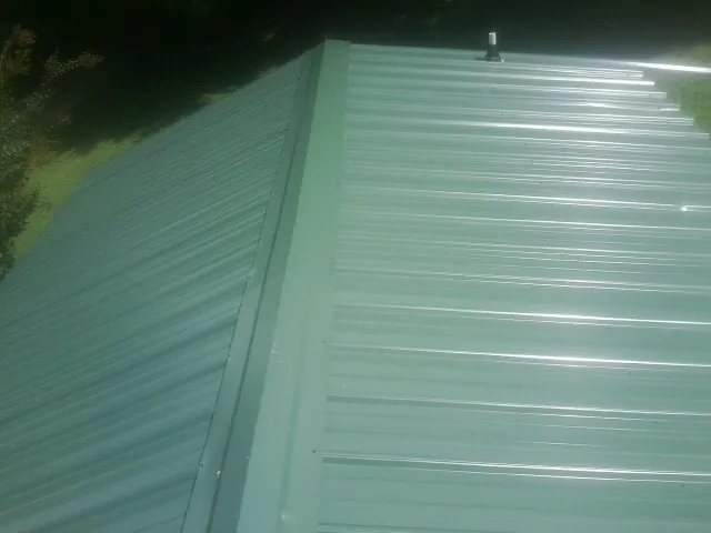 New green metal panels meeting at the ridge of a roof — Flat Roof Repair work by our crew in Keysville