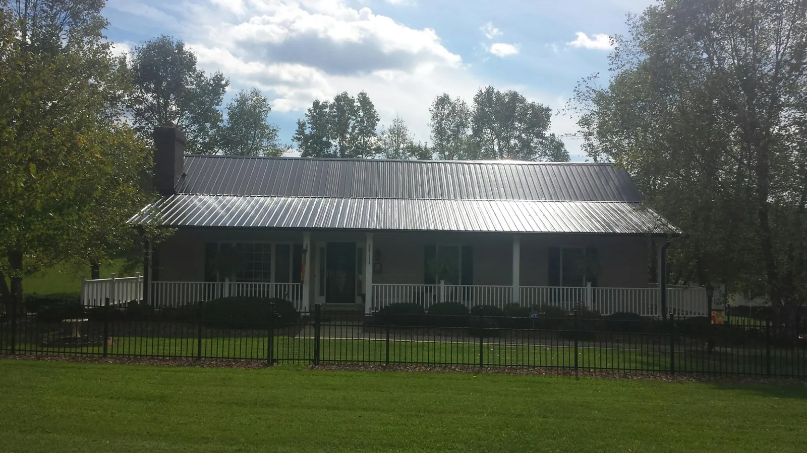 Gray metal roof on a brick ranch with a full width front porch — Gutter Guard Installation work by our crew in Keysville
