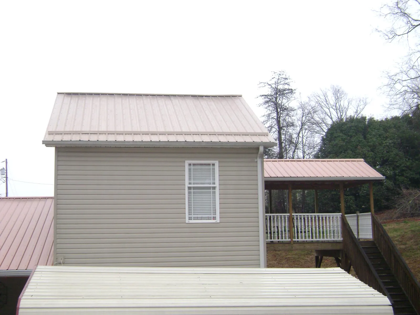 Tan metal roofs on a two story addition and attached porch, from a Roof Replacement job in Keysville