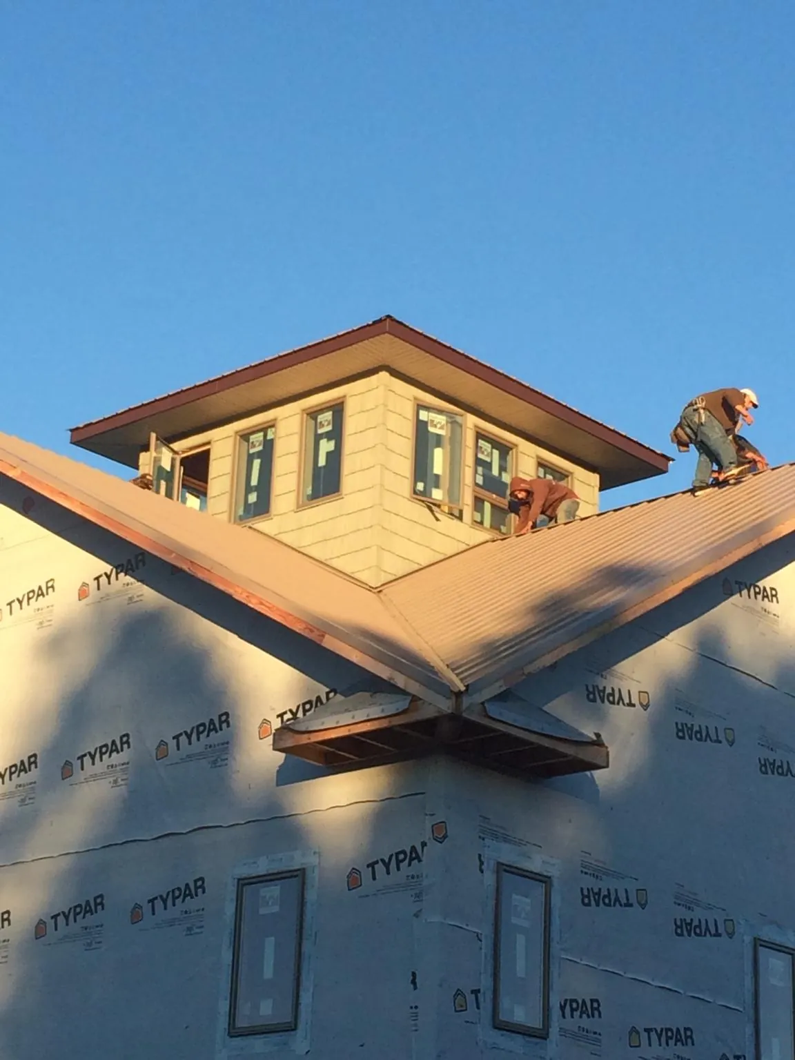 Roofers working around a rooftop cupola on a new metal roof at sunset — Roof Waterproofing in Keysville by Roofing Brothers